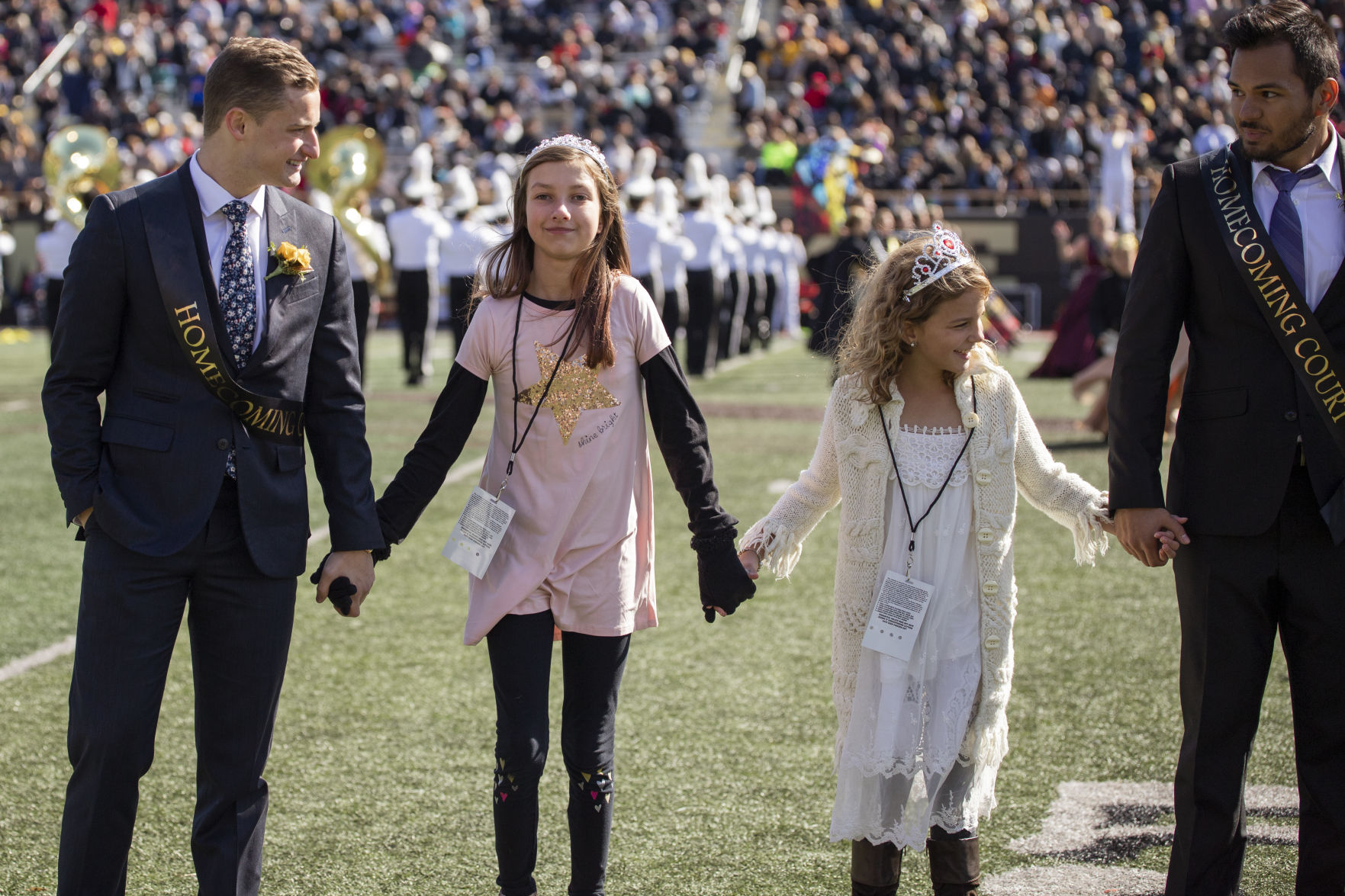 Western Michigan's homecoming court hold hands with kids